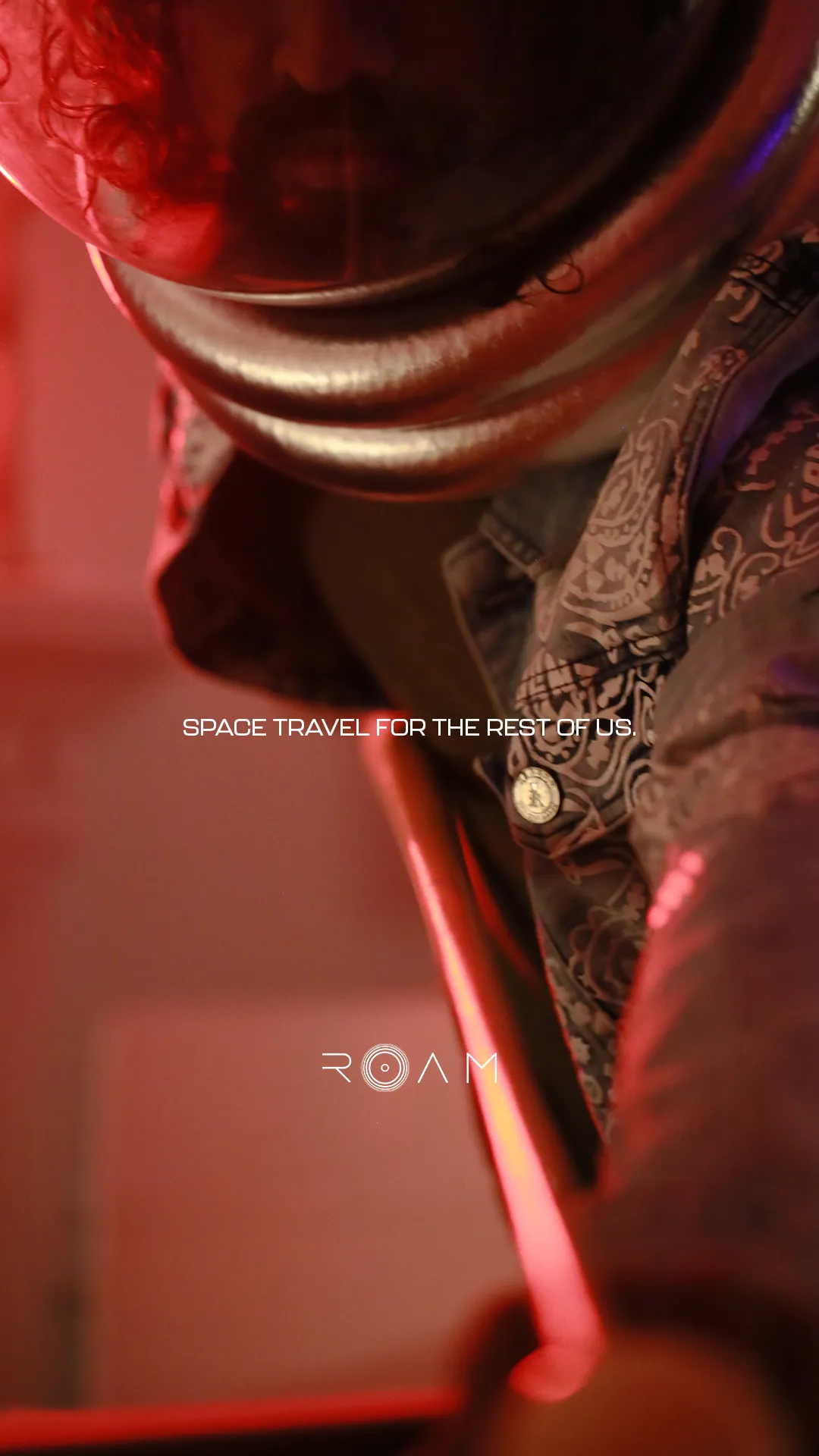 Close-up of a person wearing a space helmet and patterned jacket under red lighting with text reading 'Space travel for the rest of us' and 'ROAM'.