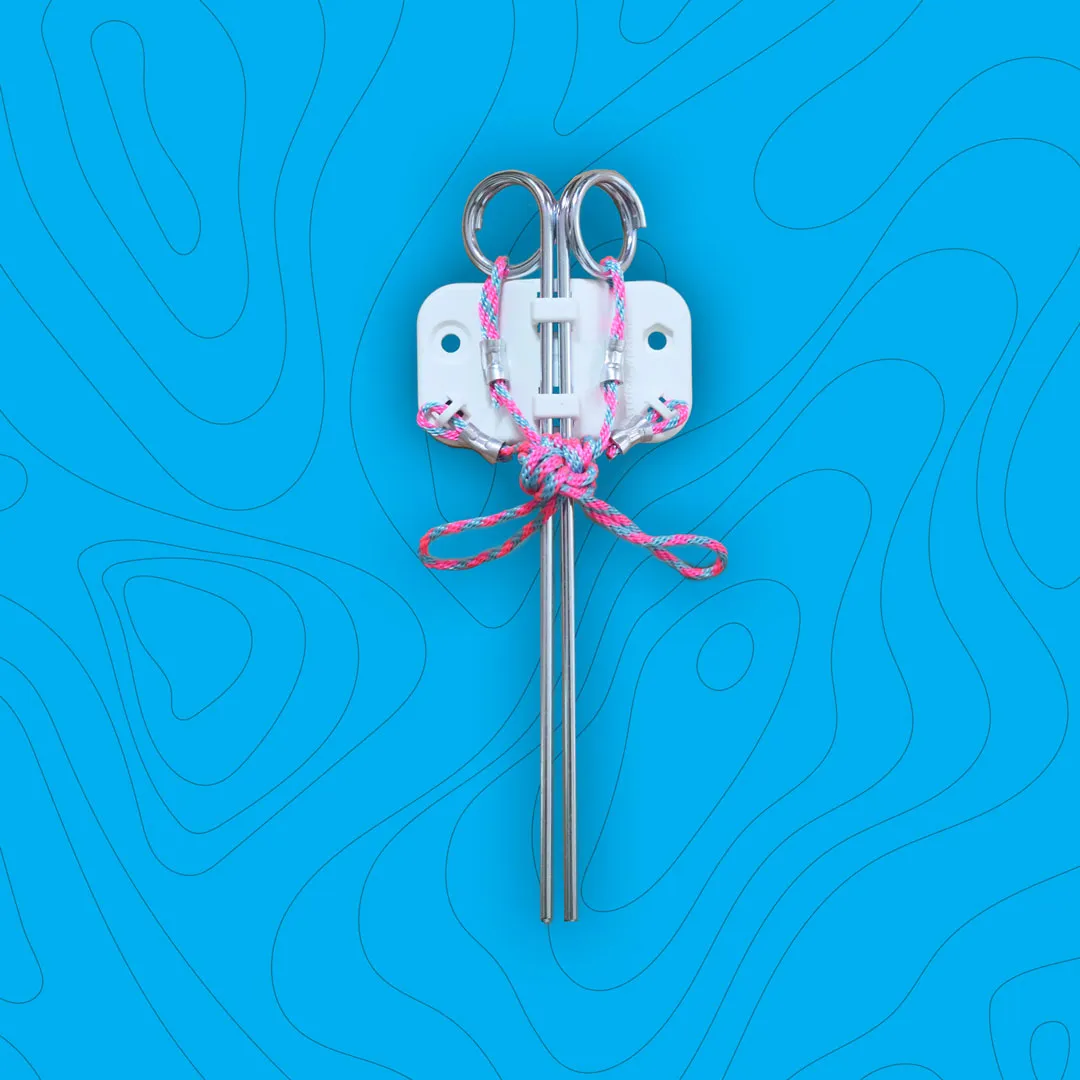 Metal anchor with two long prongs and pink-and-blue tied rope attached to a white mounting plate on a blue background.