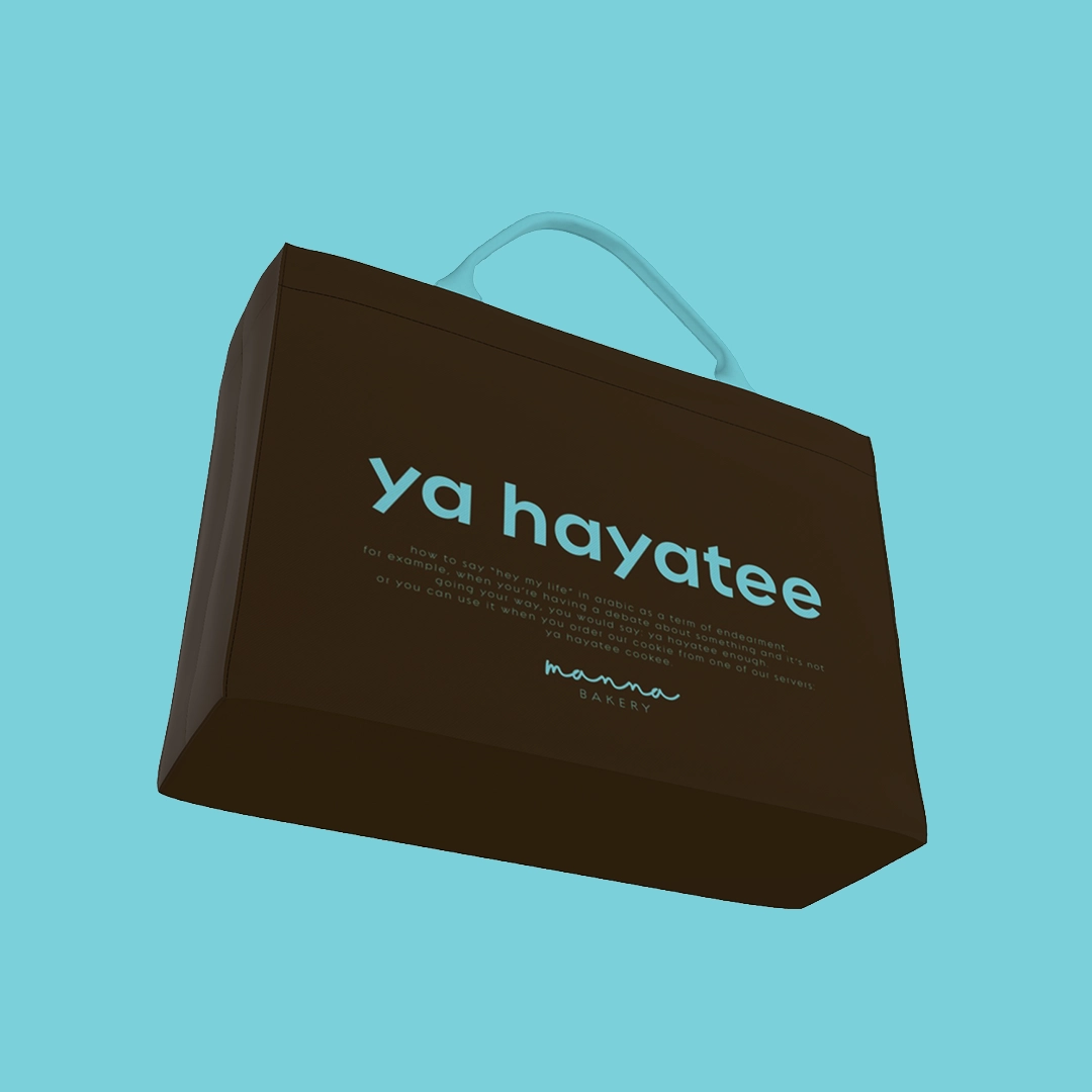 Brown bakery bag with blue handles labeled 'ya hayatee' from Manna Bakery on a blue background.