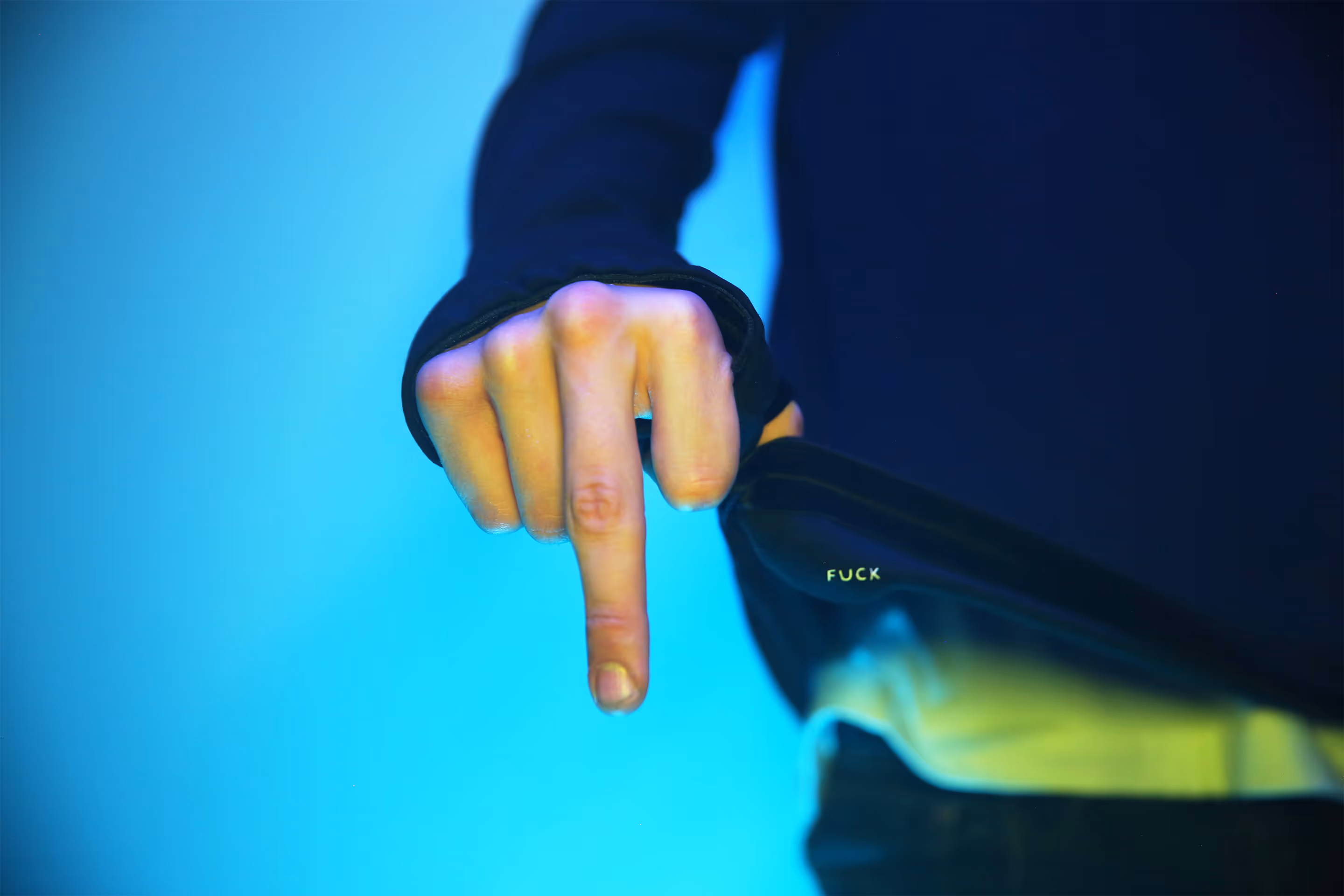 A black and white picture of a person holding a TKINK designer white t-shirt with a small printed "FUCK" over their head.